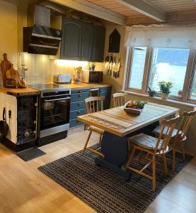 uma cozinha com uma mesa de madeira e cadeiras numa cozinha em Secluded Holiday Home, With private beach em Ålesund