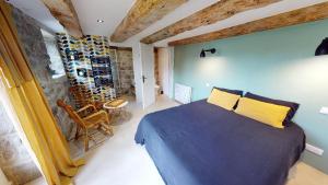 a bedroom with a blue bed and a stone wall at Une pause en Corrèze in Sarroux