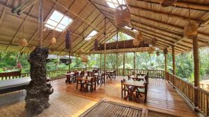 un restaurante con mesas y sillas en un suelo de madera en Rimba eco Resort, en Tomohon