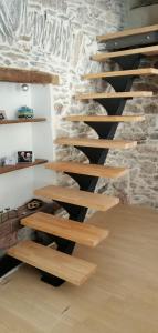 escalera de madera en una habitación con pared de piedra en La Maison du Voyageur, en Les Ilhes