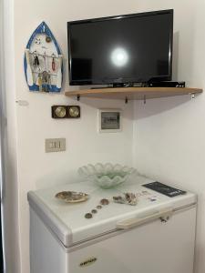 TV en una pared sobre una nevera blanca en Casa Spaziosa al centro di Ustica, en Ustica
