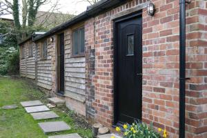 Una casa de ladrillo con una puerta negra. en Cosy secret cottage in a beautiful walled garden en Ryton