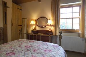 1 dormitorio con cama, espejo y ventana en Cosy secret cottage in a beautiful walled garden en Ryton