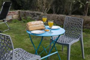 a blue table with two chairs and two glasses of orange juice at Cottage - Sleeps 2 - Garden - Parking in Ryton +5 photos