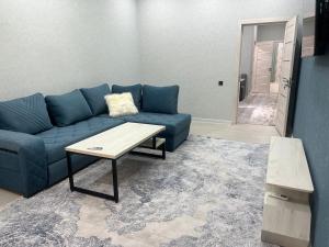 uma sala de estar com um sofá azul e uma mesa de centro em Comfortable 3-roomed apartment Ozod Apartments em Samarkand