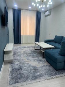 een woonkamer met een blauwe bank en een tafel bij Comfortable 3-roomed apartment Ozod Apartments in Samarkand