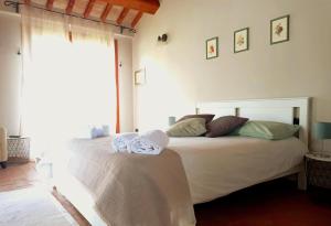una camera da letto con un letto bianco e asciugamani di Tenuta Le Garzaie - Villa Furlo a Fermignano
