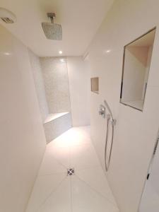 a white bathroom with a shower and a mirror at Havre de paix in Ville-dʼAvray