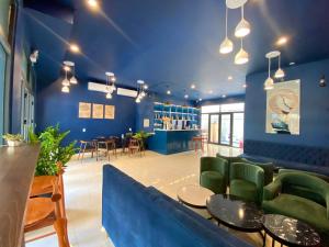 Sel de Mer Apartment Grand World Phu Quoc في فو كووك: لوبي بجدران زرقاء وكراسي وطاولات خضراء