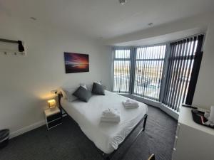 a bedroom with a bed with white sheets and windows at Blackpool Resort Hotel in Blackpool