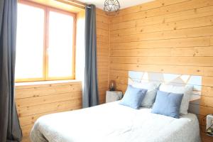 sypialnia z drewnianymi ścianami i łóżkiem z niebieskimi poduszkami w obiekcie Maison ecologique en paille w mieście La Chapelle-Enchérie