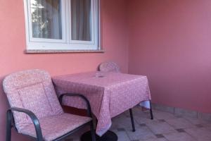 einen rosa Tisch und Stühle mit einem Tisch und einem Fenster in der Unterkunft Villa Chiara in Krnica