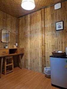 a room with a wooden wall with a desk and a refrigerator at คูณ-เนื่อง ฟาร์ม สเตย์ หัวหิน Koon & Nueang Farm Stay Hua Hin in Ban Bo Fai (1)