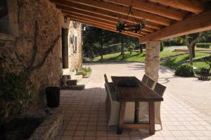 um pátio com uma mesa de madeira e cadeiras sob um telhado de madeira em Can Bora Lodges em Las Serras