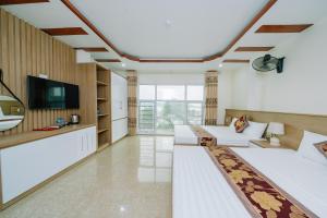 uma sala de estar com mobiliário branco e uma televisão de ecrã plano em My Ngoc Hotel em Ilha de Cát Bà