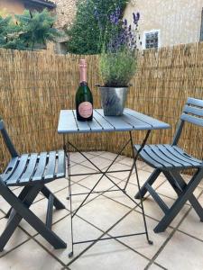 a picnic table with a bottle of wine and two chairs at The Lavender in Limoux