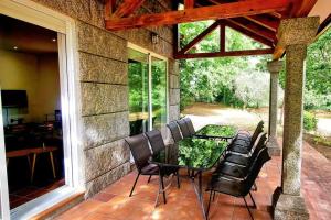 eine Terrasse mit einem Glastisch und Stühlen in der Unterkunft Casa MATRIA in Ponteareas
