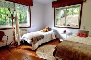 Un dormitorio con 2 camas y un osito de peluche en una cama en Casa MATRIA, en Ponteareas