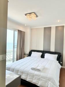 a bedroom with a large white bed with a chandelier at บ้านชายทะเล ที่พักติดทะเล ระยอง หาดแสงจันทร์ in Rayong