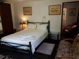 una camera con letto, lenzuola bianche e divano di AANDRUS BNB a Kestell