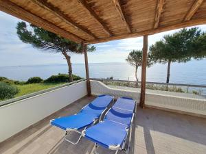 two blue lounge chairs on a porch overlooking the ocean at Beach House Kotrona in Achladi