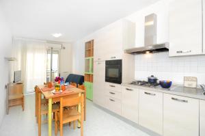 a kitchen with white cabinets and a table with a dining room at Cristoforo Colombo in Caorle