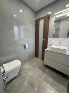 a bathroom with a sink and a toilet and a mirror at Apartament Olivia Business Suite in Gdańsk