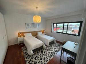 1 dormitorio con 2 camas y ventana en Conforto, espaço e localização, en Ribeira Grande