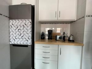 a kitchen with white cabinets and a refrigerator at Conforto, espaço e localização in Ribeira Grande