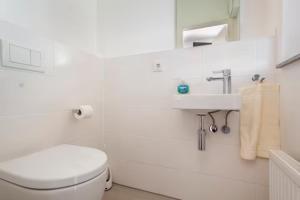 a white bathroom with a toilet and a sink at Beautiful room with balcony direction to Messe in Hannover