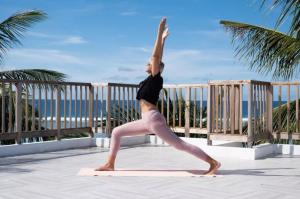 Eine Frau, die eine Yoga-Pose auf einer Yogamatte macht. in der Unterkunft Si! Coral Inn in Thulusdhoo
