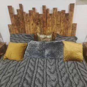 een bed met een houten hoofdeinde en gele kussens bij F2 Mass & Bo in Thaon-les-Vosges