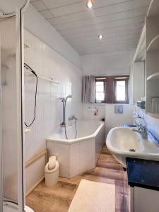 uma casa de banho branca com uma banheira e um lavatório em Schöne Altbauwohnung mit großer Sonnenterrasse em Rudolstadt