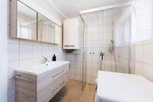 een witte badkamer met een wastafel en een douche bij Kuscheliges Häuschen in idyllischer Nachbarschaft in Innsbruck