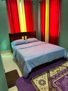 a bedroom with red and yellow curtains and a bed at Cassa Vistana Homestay Alor - Langgar near HSB in Alor Setar