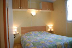 a bedroom with a bed and two lights on the wall at Mobile Home La Tranche sur Mer 6 personnes in Angles