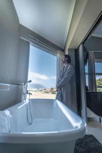 a man standing in a bathroom with a bath tub at Gaia Hydro-Spa and Guest House in Cape Town