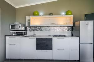 a white kitchen with a sink and a refrigerator at Gaia Hydro-Spa and Guest House in Cape Town