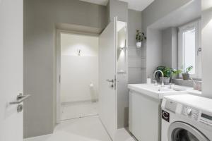 a white bathroom with a sink and a washing machine at Exklusiv: Historisches Apartment mit Deckengewölbe in Munich