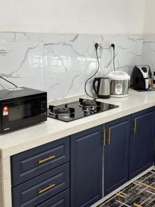 eine Küche mit blauen Schränken und einer schwarzen Mikrowelle in der Unterkunft Cassa Vistana Homestay Alor - Langgar near HSB in Alor Setar
