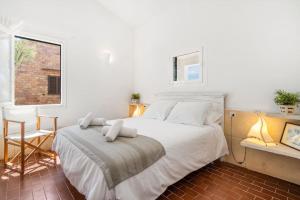 - une chambre avec un grand lit blanc et une fenêtre dans l'établissement Sa Calma, à Cala Blanca