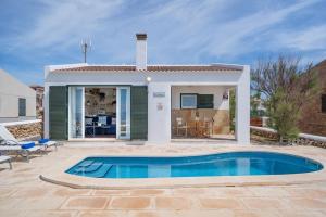 a villa with a swimming pool in front of a house at Sa Calma in Cala Blanca