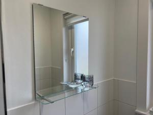a glass mirror on a wall in a bathroom at Cosy Cottage Apartment in Helensburgh