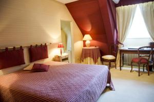 a bedroom with a bed and a desk and a window at Malouinière Le Valmarin in Saint Malo