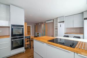 a kitchen with white cabinets and a wooden counter top at Luxury Apartment located near Marble Arch & Baker Street in London