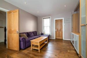 ein Wohnzimmer mit einem lila Sofa und einem Tisch in der Unterkunft Luxury Apartment located near Marble Arch & Baker Street in London