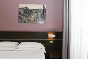 1 dormitorio con 1 cama y una foto en la pared en Hotel Vienna, en Lido di Jesolo