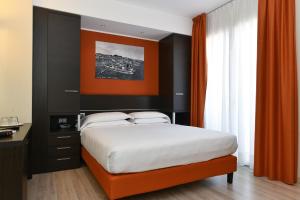 1 dormitorio con 1 cama grande y pared de color naranja en Hotel Vienna en Lido di Jesolo