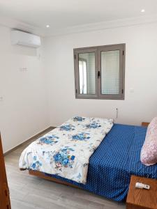 una camera da letto con un letto con un piumone blu e una finestra di Résidence Inès Djerba Appartement de Luxe a Houmt Souk