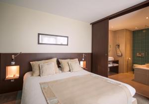 1 Schlafzimmer mit einem großen Bett und einem Badezimmer in der Unterkunft Hotel du Pasino in Saint-Amand-les-Eaux